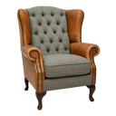 A classic wingback armchair featuring tan leather arms and backrest, tufted button detailing, and a check Harris Tweed seat and back cushion, set against a plain white background.